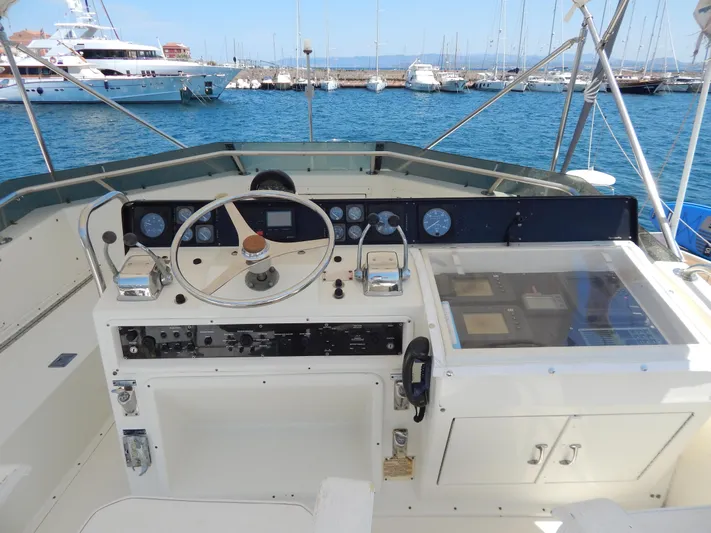  Yacht Photos Pics 1989 Hatteras 45 Convertible yacht helm with steering wheel and control panel, docked at marina.