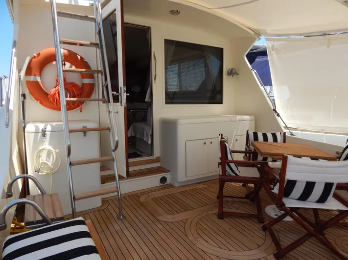  Yacht Photos Pics 1989 Hatteras 45 Convertible yacht deck with striped seating and wooden table.