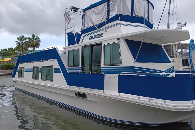 Ski Breeze Yacht Photos Pics 1996 Harbor Master 52 Wide Body houseboat with blue accents docked on a cloudy day.