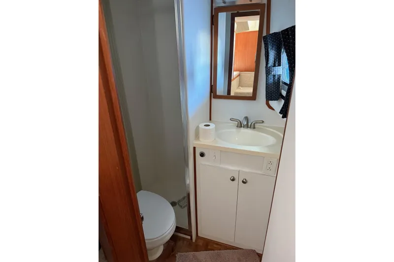 Ski Breeze Yacht Photos Pics Bathroom interior of 1996 Harbor Master 52 Wide Body yacht, featuring sink, mirror, and toilet.