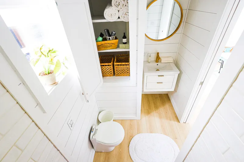  Yacht Photos Pics Modern bathroom on Hank's 40 Houseboat, featuring white decor, round mirror, and wooden accents.