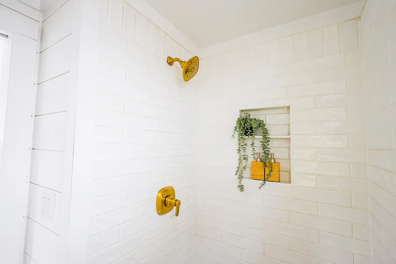  Yacht Photos Pics Luxurious white-tiled shower with gold fixtures and a plant accent on Hank's 40 Houseboat, 2025.