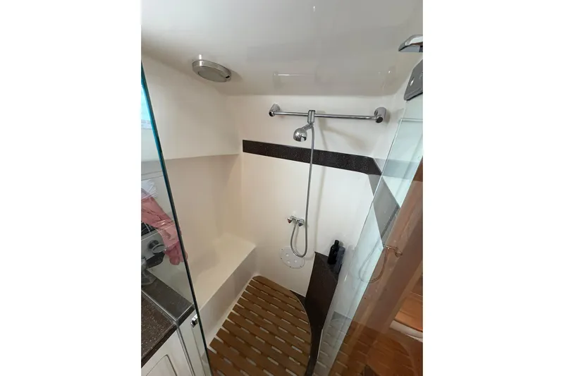 N'baluba Yacht Photos Pics Compact shower area in 2008 Rivolta Coupe 4.5, featuring glass door and wooden floor mat.