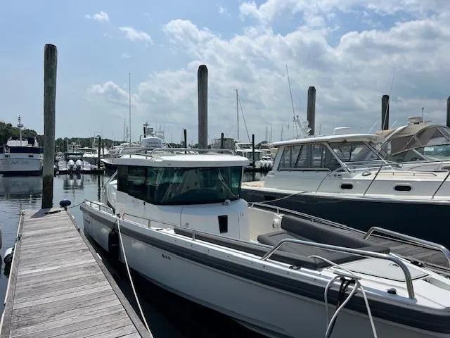  Yacht Photos Pics 2019 Axopar 28 boat docked at a marina under a partly cloudy sky.
