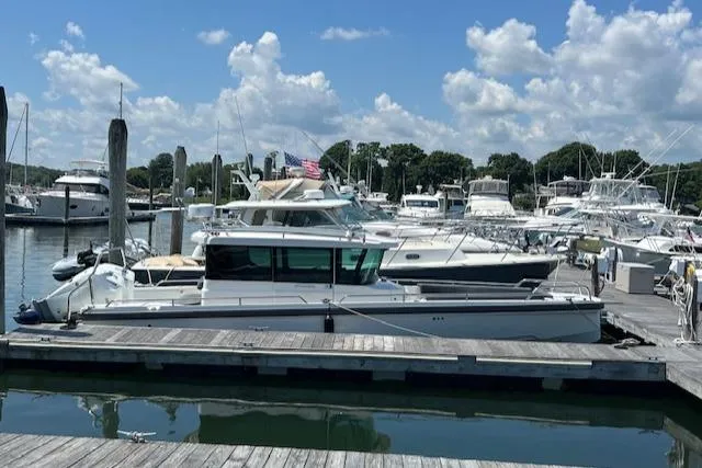  Yacht Photos Pics 2019 Axopar 28 boat docked at a marina under a partly cloudy sky.