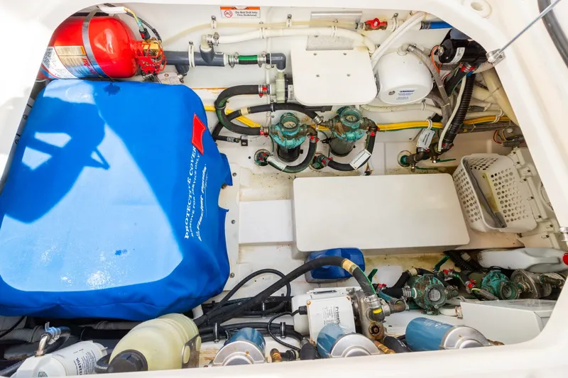 Pirates Bight Yacht Photos Pics Engine compartment of a 2019 Pursuit 408 boat, featuring various mechanical components and a fire extinguisher.