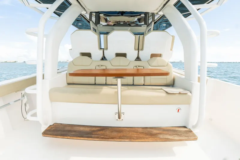 Pirates Bight Yacht Photos Pics 2019 Pursuit 408 boat interior with beige seating and wooden table, on calm water.
