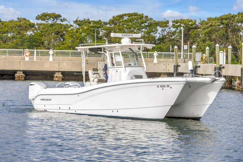  Yacht Photos Pics 2021 World Cat 295 CC boat on water near dock, clear sky background.