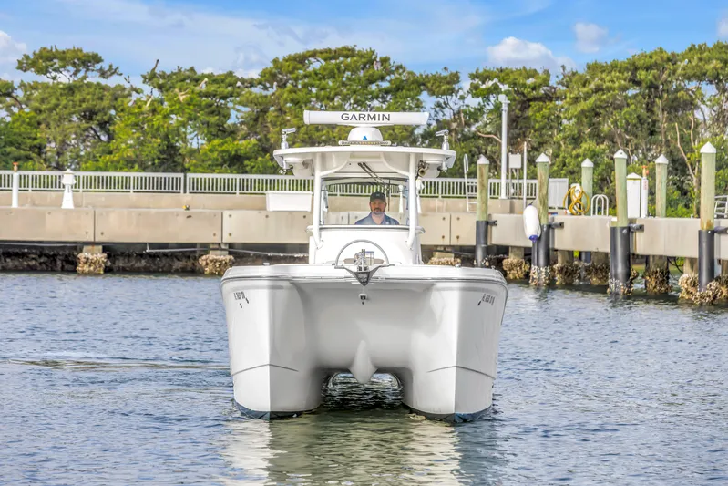  Yacht Photos Pics 2021 World Cat 295 CC boat approaching dock, clear sky, calm water.