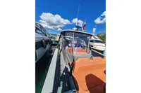 2022 Saxdor 320 GTO boat with orange seating, docked under a clear blue sky.
