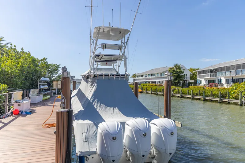  Yacht Photos Pics 2023 Edgewater 370CC boat docked with cover, featuring triple outboard engines.