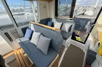 Interior of 2023 Nimbus C11 boat with cushioned seating and marina view.