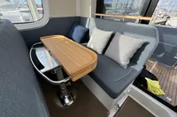 Cozy seating area in 2023 Nimbus C11 boat with cushions and wooden table.