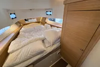Cozy cabin interior of 2023 Nimbus C11 boat with comfortable bedding and wooden accents.