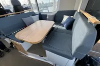 2023 Nimbus C11 boat interior with blue seating, wooden table, and cushions.