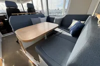 Luxurious interior of 2023 Nimbus C11 boat with cozy seating and elegant wooden table.
