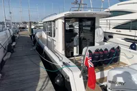 2023 Nimbus C11 boat docked at marina with Mercury engine and red flag.