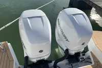 Twin Mercury outboard engines on a 2023 Nimbus C11 boat, docked on calm water.