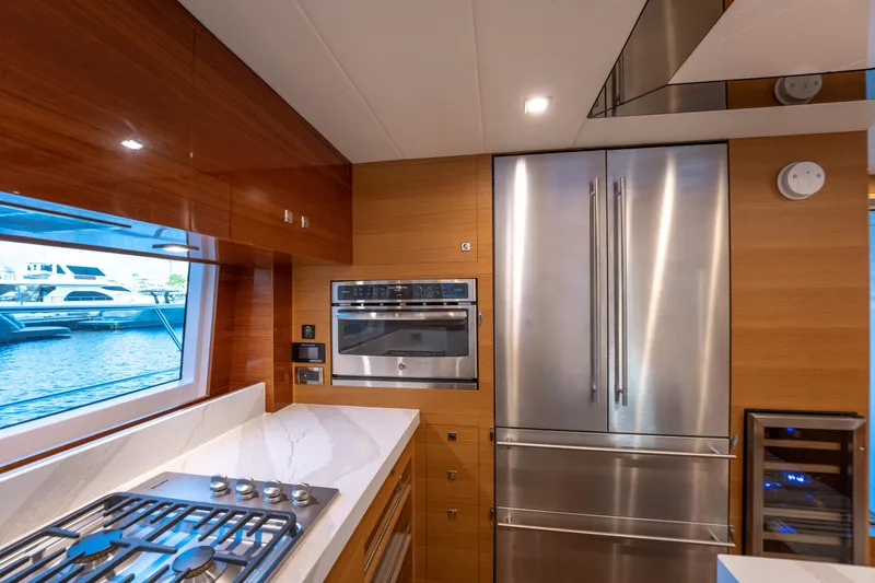 Mystic Soul Yacht Photos Pics Modern yacht kitchen with stainless steel appliances, wooden cabinetry, and ocean view window. Horizon PC52, 2019.