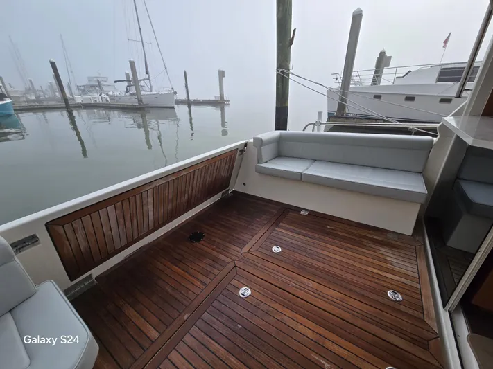 Latitude Adjustment Yacht Photos Pics Deck of 2022 Greenline 39 Hybrid yacht with wooden flooring and cushioned seating.