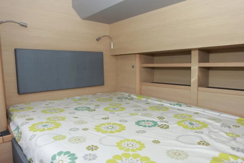  Yacht Photos Pics Cozy bedroom interior of 2023 Aquila 44 Yacht with floral bedding and wooden shelves.