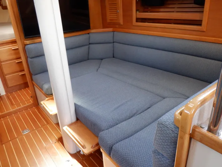Tapawingo Yacht Photos Pics Interior of 1998 Pacific Seacraft 40 sailboat with blue cushioned seating and wooden flooring.