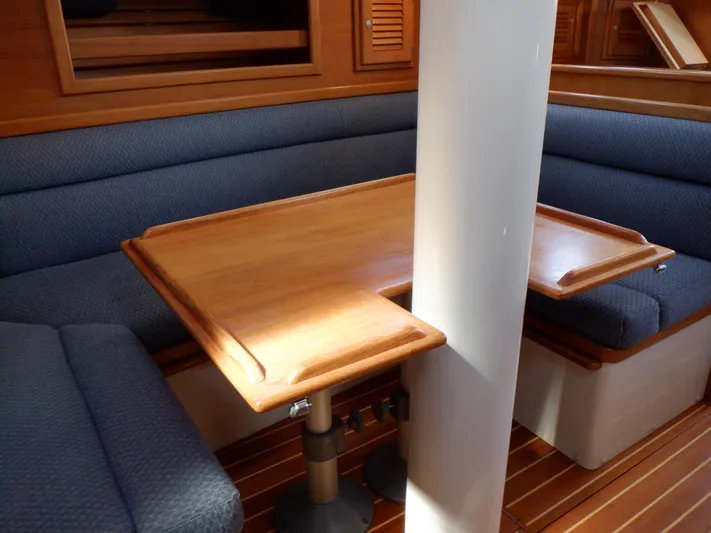 Tapawingo Yacht Photos Pics Interior of 1998 Pacific Seacraft 40 sailboat with wooden table and blue cushioned seating.
