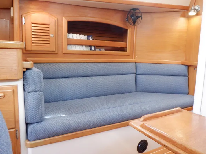 Tapawingo Yacht Photos Pics Interior of 1998 Pacific Seacraft 40 sailboat with blue cushioned seating and wooden cabinetry.