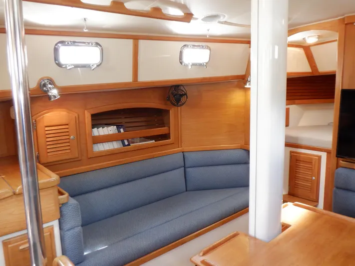 Tapawingo Yacht Photos Pics Interior of 1998 Pacific Seacraft 40 sailboat with blue seating and wooden cabinetry.