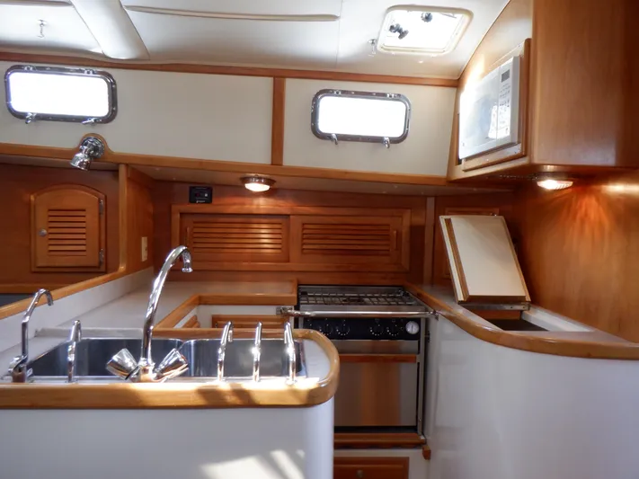 Tapawingo Yacht Photos Pics Interior of 1998 Pacific Seacraft 40 sailboat kitchen with wood finish and stainless steel sink.