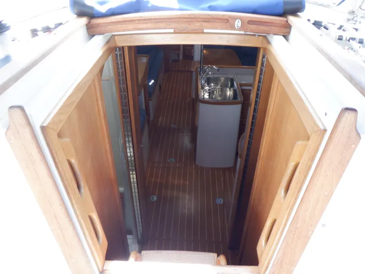 Tapawingo Yacht Photos Pics Interior view of 1998 Pacific Seacraft 40 sailboat, featuring wooden flooring and compact kitchen area.