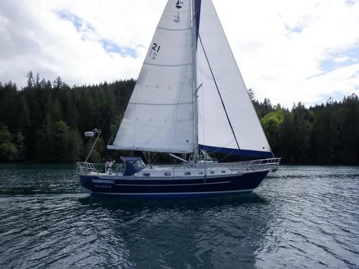 Tapawingo Yacht Photos Pics 1998 Pacific Seacraft 40 sailboat cruising on a serene lake with forested background.