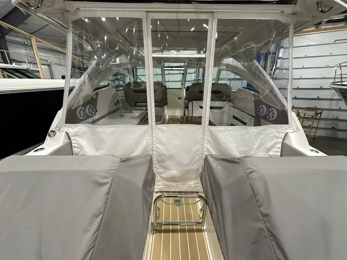 Tinkers Toye Yacht Photos Pics 2024 Tiara Yachts 34 LX interior with covered seating and clear enclosure in a showroom.