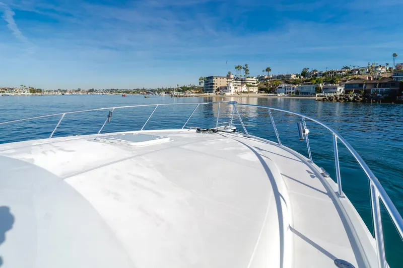 Apothecary Yacht Photos Pics 2011 Cabo Express boat cruising near coastal homes under clear blue skies.