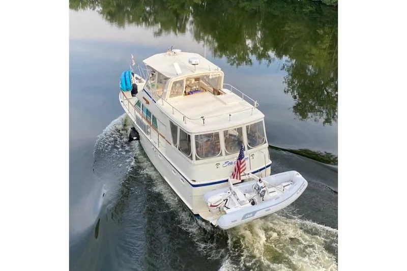 Sea Breeze Yacht Photos Pics 1985 Hatteras 43 Motor Yacht cruising on calm water with American flag.