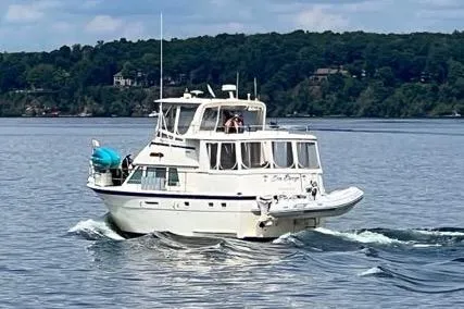 Sea Breeze Yacht Photos Pics 1985 Hatteras 43 Motor Yacht cruising on a serene lake with forested shoreline.