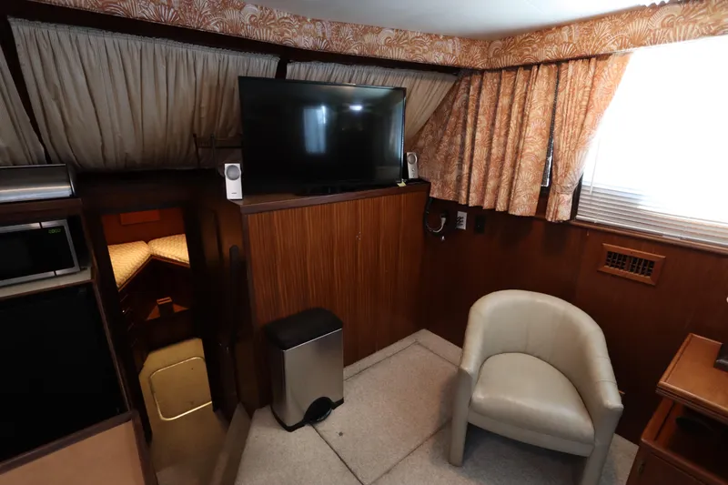 Sea Breeze Yacht Photos Pics Interior of 1985 Hatteras 43 Motor Yacht with TV, chair, and wood paneling.
