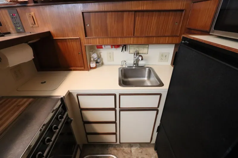 Sea Breeze Yacht Photos Pics 1985 Hatteras 43 Motor Yacht kitchen with sink, stove, and wooden cabinets.