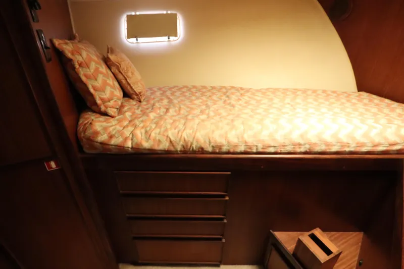 Sea Breeze Yacht Photos Pics 1985 Hatteras 43 Motor Yacht cabin with bed, drawers, and patterned bedding.