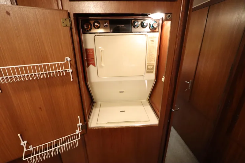 Sea Breeze Yacht Photos Pics Laundry area inside 1985 Hatteras 43 Motor Yacht with wooden cabinetry and dryer.
