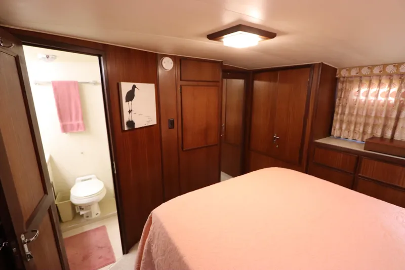 Sea Breeze Yacht Photos Pics 1985 Hatteras 43 Motor Yacht interior cabin with ensuite bathroom, wood paneling, and pink bedding.