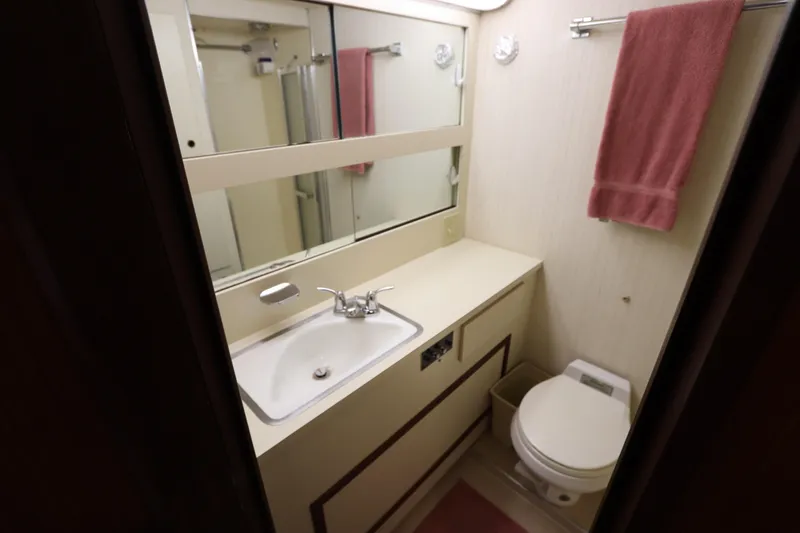 Sea Breeze Yacht Photos Pics Bathroom interior of 1985 Hatteras 43 Motor Yacht with sink, toilet, and mirror.