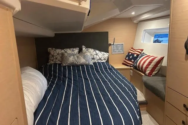 Agua Especial Yacht Photos Pics Cozy cabin interior of 2016 Jeanneau 54 yacht with striped bedding and decorative pillows.