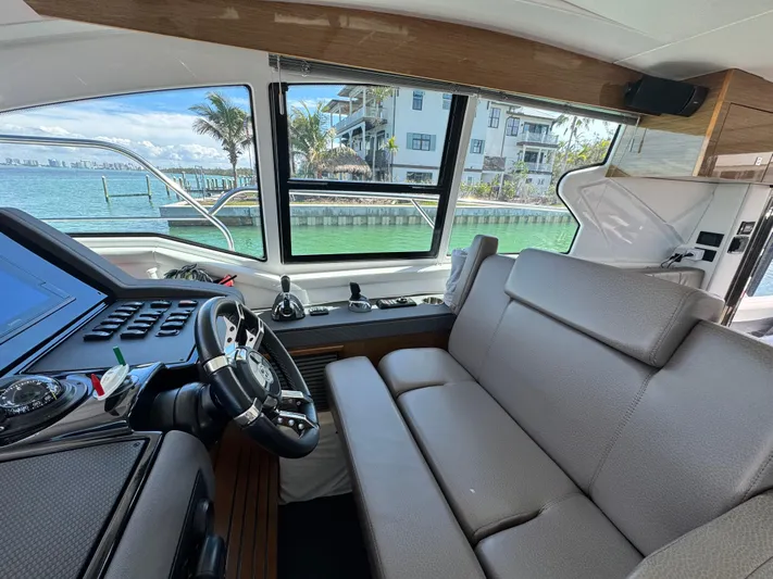 Truly Ineffable Yacht Photos Pics Interior of 2019 Cruisers Yachts 42 Cantius with helm and seating, overlooking waterfront.