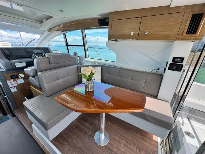 Truly Ineffable Yacht Photos Pics 2019 Cruisers Yachts 42 Cantius interior with elegant seating and wooden table, overlooking the ocean.