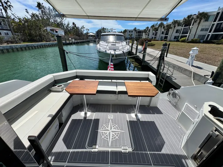 Truly Ineffable Yacht Photos Pics 2019 Cruisers Yachts 42 Cantius docked, featuring spacious outdoor seating and dual tables.