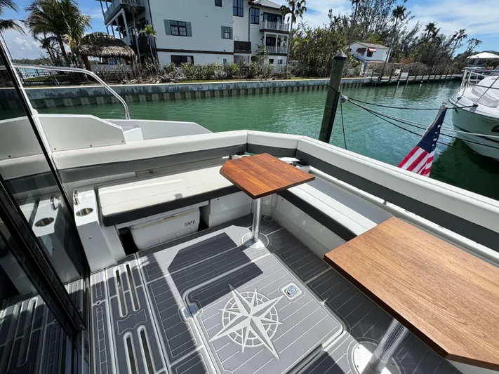 Truly Ineffable Yacht Photos Pics 2019 Cruisers Yachts 42 Cantius deck with wooden tables, docked by a canal.