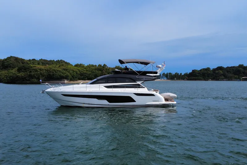  Yacht Photos Pics 2023 Fairline Squadron 50 yacht cruising on serene waters with lush greenery backdrop.