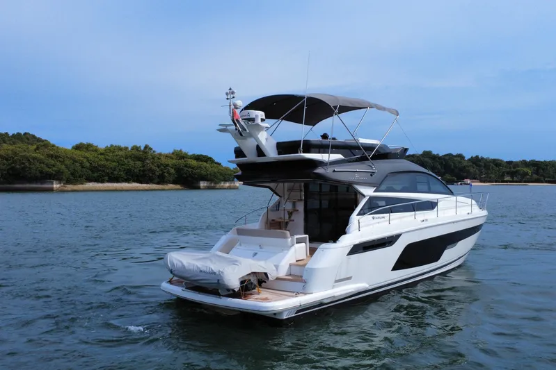  Yacht Photos Pics 2023 Fairline Squadron 50 yacht cruising on serene waters near a lush shoreline.