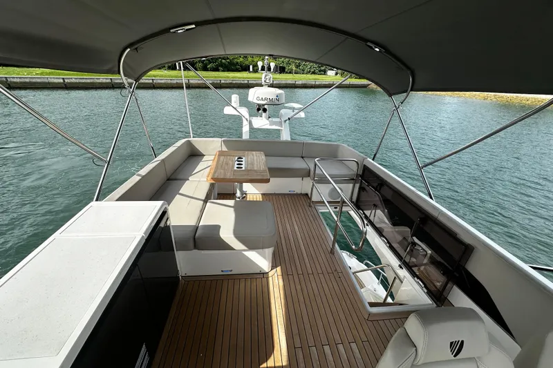  Yacht Photos Pics Luxurious 2023 Fairline Squadron 50 yacht deck with seating and table, overlooking serene water.